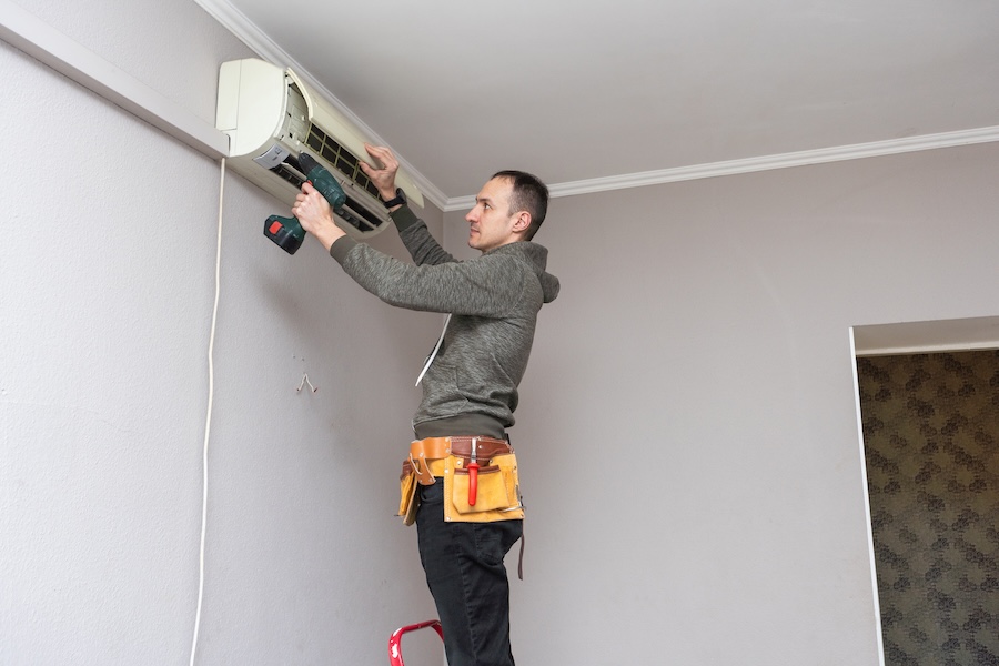 man repairing air conditioner with power tool 2026 03 16 04 26 55 utc
