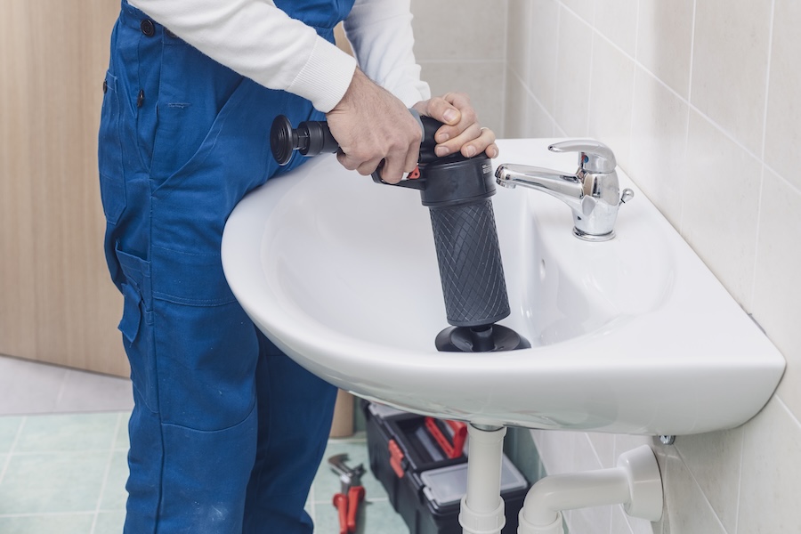 plumber using plunger device in bathroom sink 2026 03 09 08 13 14 utc